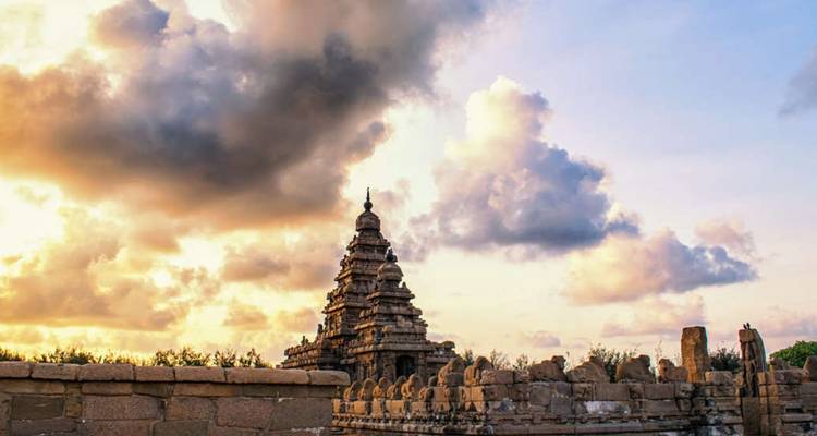 Antiker Küstentempel als Silhouette vor dramatischen Sonnenuntergangswolken an der Küste.