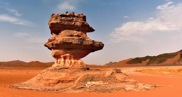 Towering red sandstone mushroom rock formation rising from the Sahara desert sands