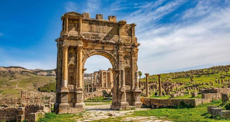Well-preserved Roman triumphal arch leading to ancient colonnades amid rolling hills