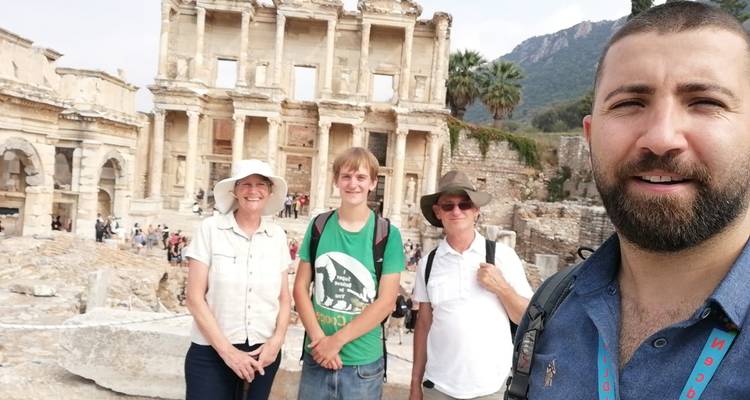 Des touristes posent avec un guide devant l'ancienne façade de la bibliothèque de Celsus