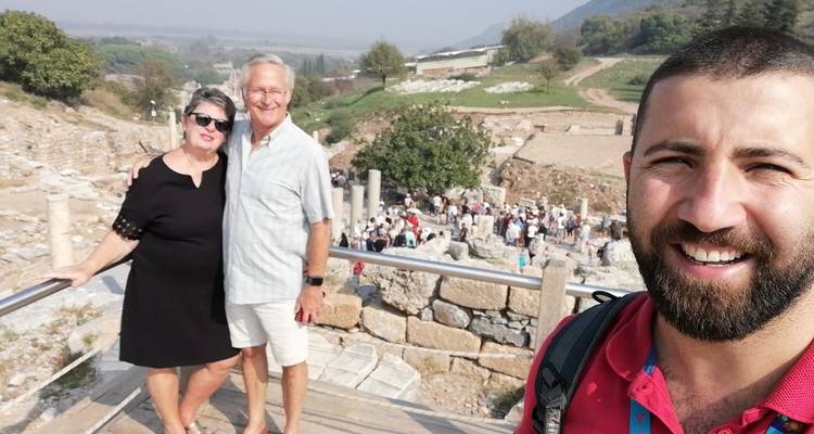 Guide prend un selfie avec un couple âgé surplombant un site archéologique animé
