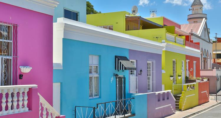 Maisons mitoyennes vibrantes de Bo-Kaap peintes en rose, bleu et jaune sous le ciel dégagé du Cap.