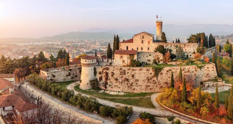 Vue panoramique du château de Brescia perché au-dessus de la ville aux teintes automnales dans la douce lumière du crépuscule.