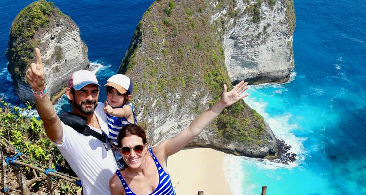 Famille posant avec enthousiasme au-dessus d'une plage de sable blanc isolée et d'eaux bleues