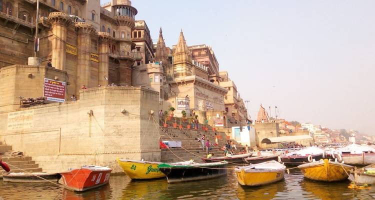 Historische Ghats und Tempel entlang des Ganges mit bunten Booten in Varanasi
