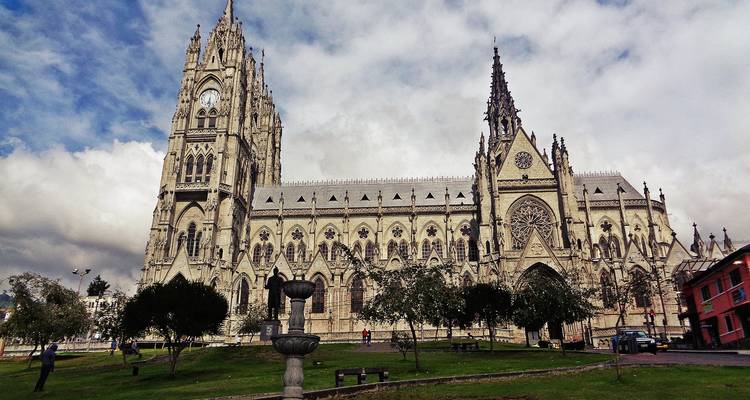 De sierlijke neogotische Basílica del Voto Nacional domineert een grasrijk plein onder een dramatische bewolkte hemel in Quito.