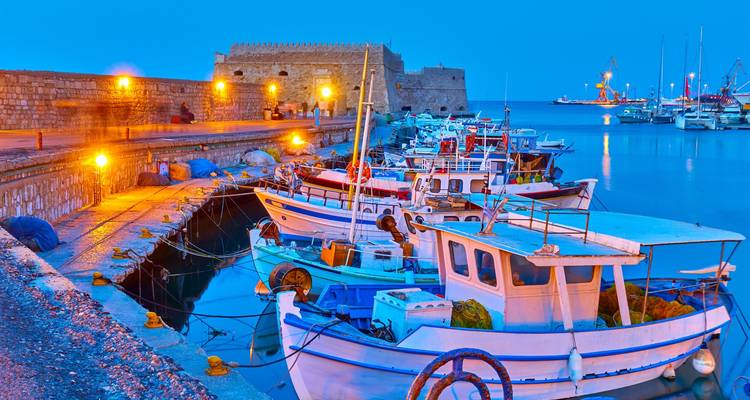Les lumières du soir illuminent les bateaux de pêche près de la forteresse vénitienne dans le port d'Héraklion.