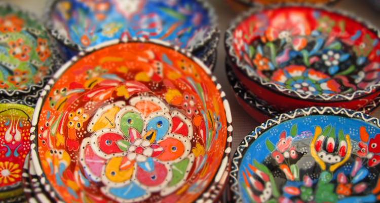 Levendig beschilderde keramische kommen met traditionele bloemenmotieven tentoongesteld in een marktomgeving.