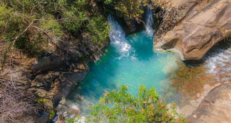 Vue de dessus d'un bassin de cascade turquoise niché dans une jungle rocheuse.