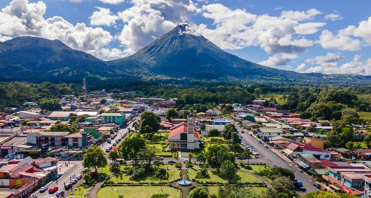 Drone view of La Fortuna town with majestic Arenal Volcano towering behind.