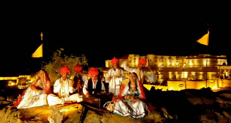 Traditionelle rajasthanische Volksmusiker treten nachts vor der Kulisse einer beleuchteten Festung auf