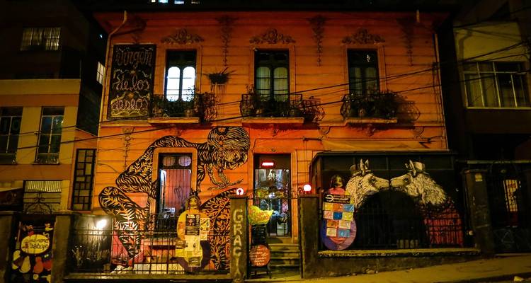 Edificio colonial cubierto de grafitis iluminado por luces cálidas en una calle de la ciudad por la noche.