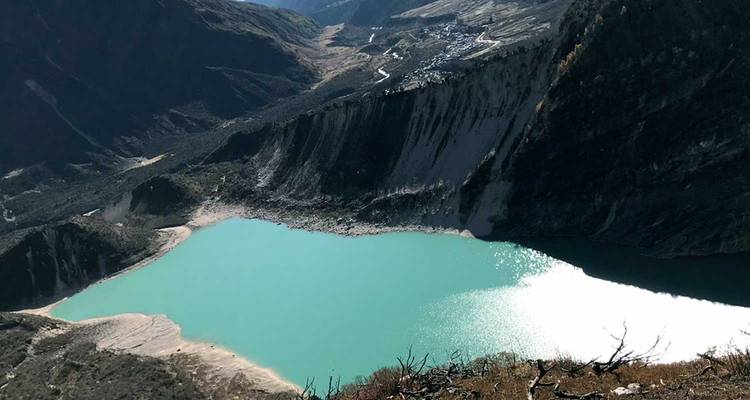 Turkooizen alpine meer ligt onder steile geërodeerde kliffen en kronkelende Himalaya-vallei.