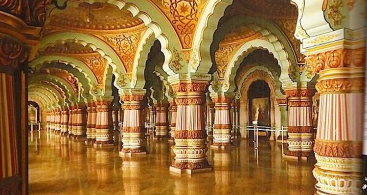 Prunkvoller Saal des Mysore-Palastes mit reich bemalten Bögen, verzierten Säulen und glänzendem Boden.