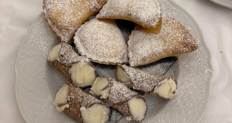 Assiette avec cannoli siciliens et pâtisseries au sucre glace sur nappe blanche