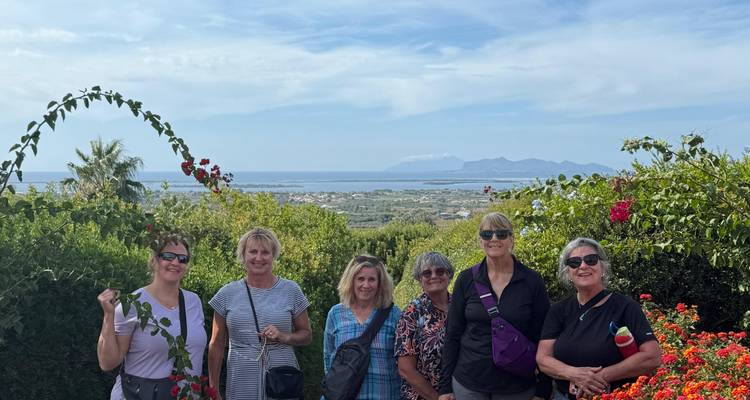 Groupe de femmes posant dans un point de vue de jardin luxuriant avec un littoral lointain et des îles en arrière-plan