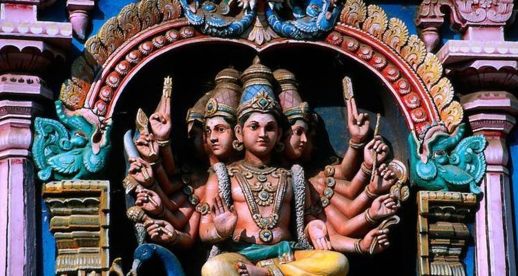 Lebendige vielarmige hinduistische Götterskulptur, reich bemalt an der Fassade eines südindischen Tempels.