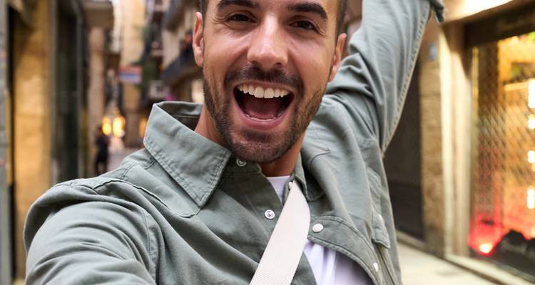 Selfie en primer plano de un viajero emocionado en una calle urbana estrecha