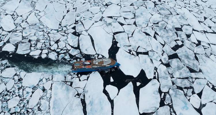 Luchtfoto van een ijsbreker die navigeert door een mozaïek van Arctisch pakijs.