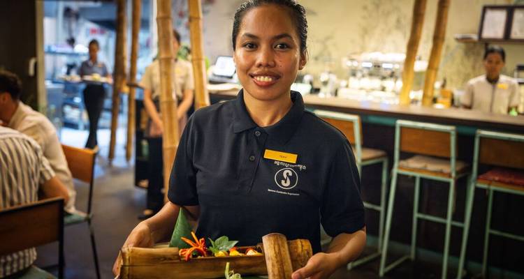 Serveuse tenant un plateau en bambou avec de la nourriture dans un restaurant cambodgien élégant