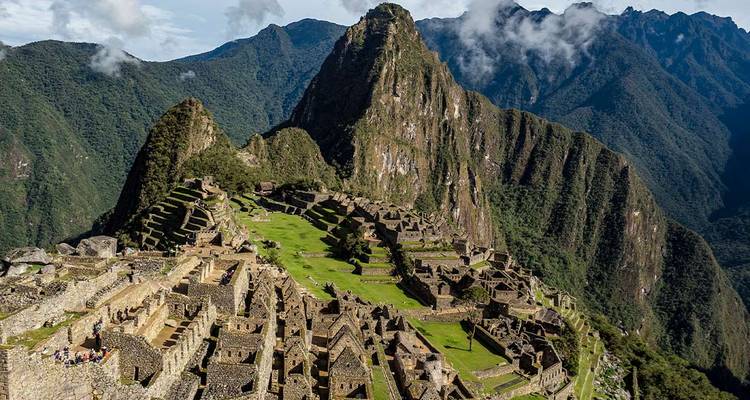 Vue aérienne emblématique des terrasses du Machu Picchu et du pic Huayna Picchu entourés par les Andes verdoyantes.