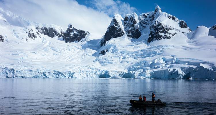 Kleine opblaasbare zodiac die avonturiers naar torenhoge blauwe gletsjerkliffen in Antarctica vervoert.