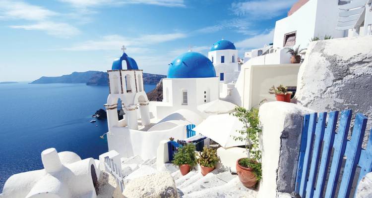 Les terrasses blanchies à la chaux emblématiques, les dômes bleus et la mer Égée scintillent sous les cieux grecs dégagés.