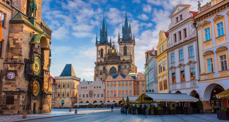 Plaza de la Ciudad Vieja en Praga con las torres góticas de la Iglesia de Týn alzándose hacia un cielo parcialmente nublado.