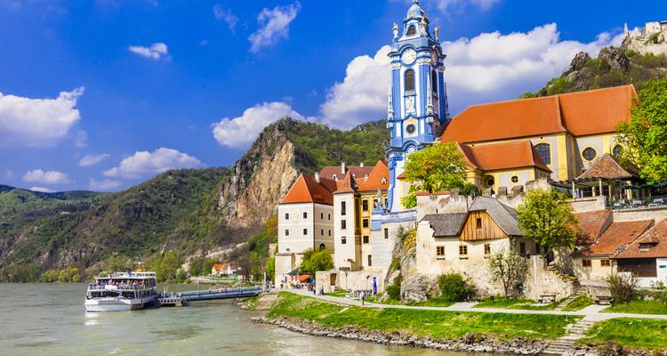 La torre azul y blanca de la Abadía de Dürnstein domina el Danubio con acantilados y pueblos cercanos.
