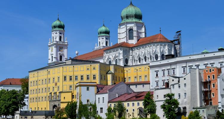 La catedral barroca de San Esteban de Passau con cúpulas verdes se eleva sobre los coloridos edificios ribereños.