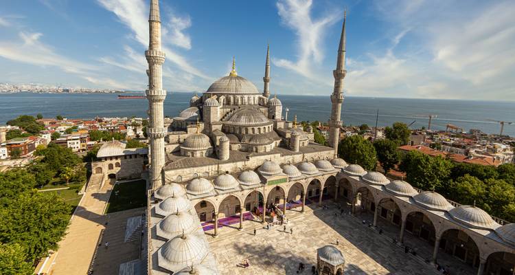 Vue aérienne de la cour de la Mosquée Bleue d'Istanbul, ses dômes et ses minarets élancés au bord du Bosphore par une journée lumineuse.