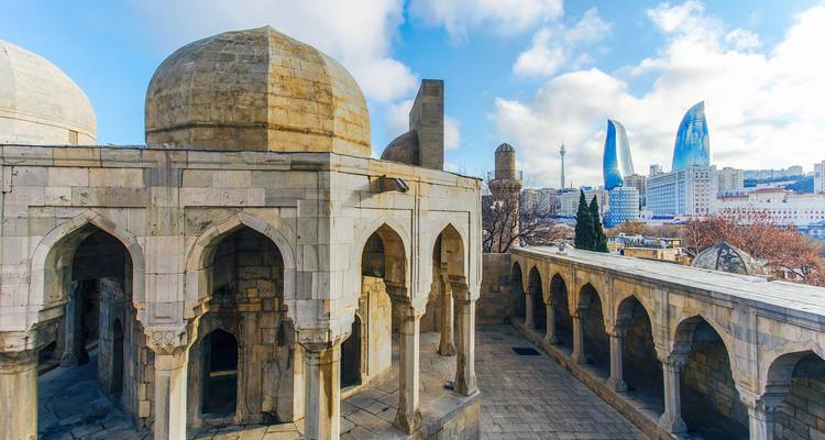 Mittelalterliche Steinbögen des Shirvanshah-Palastkomplexes mit Bakus modernen Flame Towers, die sich im Hintergrund erheben.