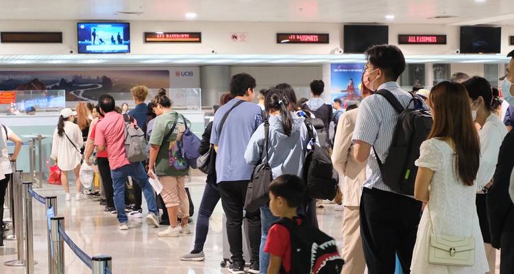 Long line of arriving passengers waits at immigration counters inside the terminal.