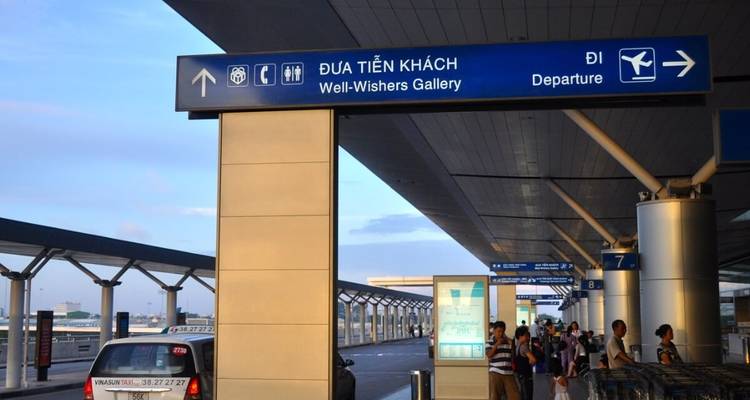 Departing travellers stand outside the terminal under well-wishers’ gallery signage.