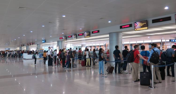 Dozens of passengers line up with luggage at visa-on-arrival counters.