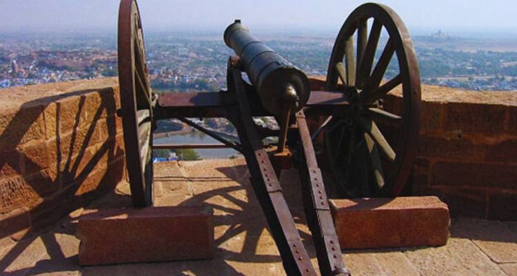 Un canon historique pointe sur le panorama de la ville bleue de Jodhpur depuis un rempart de fort.