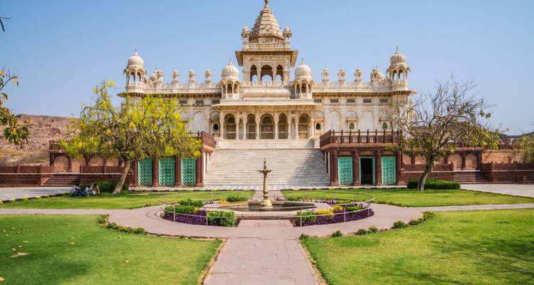 Cénotaphe en marbre orné de Jaswant Thada situé dans des jardins entretenus sous un ciel bleu dégagé.