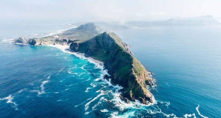 Vue aérienne de la péninsule spectaculaire du Cap Point s'avançant dans l'océan Atlantique avec des eaux turquoise tourbillonnantes