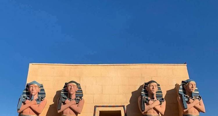 Four large pharaoh statues decorate the façade of a sandy-coloured film set against a deep blue sky.