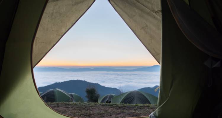 Vista de amanecer de ensueño sobre las nubes enmarcada por la solapa abierta de una tienda de campaña en el campamento del Monte Kilimanjaro