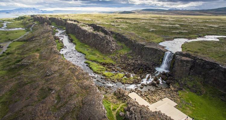 Vue aérienne de la vallée du Rift avec une cascade et des passerelles traversant le paysage dramatique du parc national de Thingvellir.