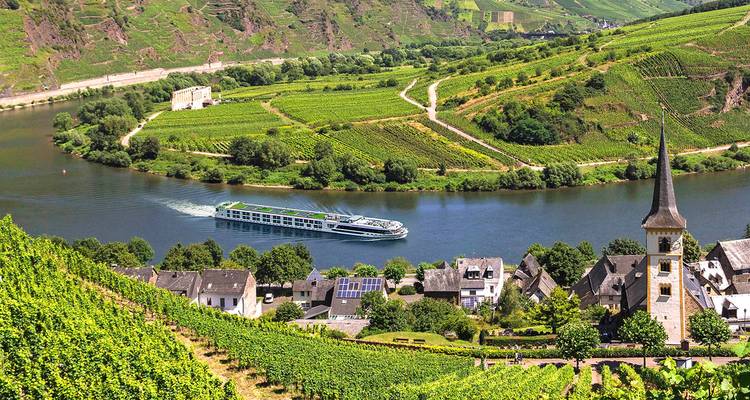 Un élégant bateau de croisière fluviale glisse le long d'un méandre de la Moselle bordé de vignobles, à côté d'un village et d'un clocher d'église.