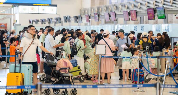 Hall d'enregistrement d'aéroport animé avec de longues files d'attente de passagers et des chariots à bagages sous un éclairage vif.