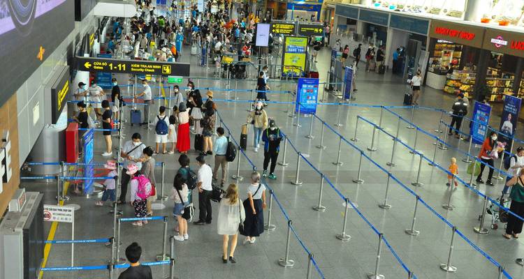Vue aérienne large d'une zone d'immigration d'aéroport bondée avec des files d'attente organisées et des écrans d'information.