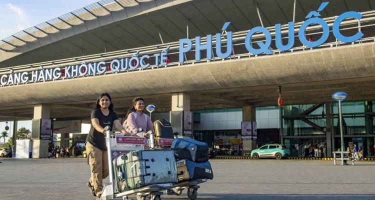 Two women push a luggage trolley outside Phu Quoc airport’s modern façade.