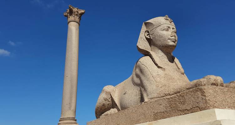 Estatua de esfinge de granito junto al Pilar de Pompeyo bajo un cielo azul despejado