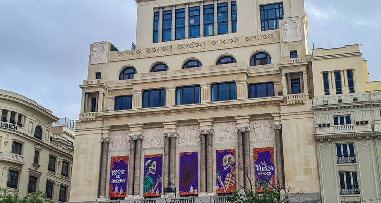 Frontfassade von Madrids Teatro Real geschmückt mit bunten Festivalbannern unter einem grauen Himmel.
