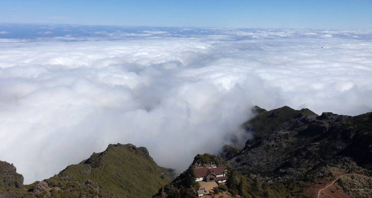 Wolkenzee bedekt het landschap onder een hoog berguitkijkpunt met een kleine berghut.