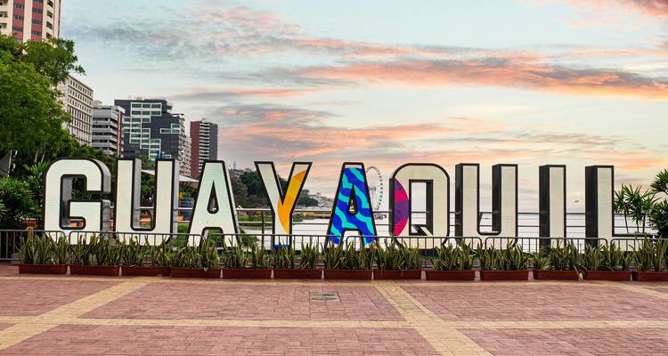 Gran letrero de GUAYAQUIL en el malecón ribereño con suave cielo del amanecer detrás