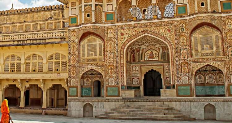 Colorful facade and intricate arches of Amber Fort with a lone sari-clad visitor.